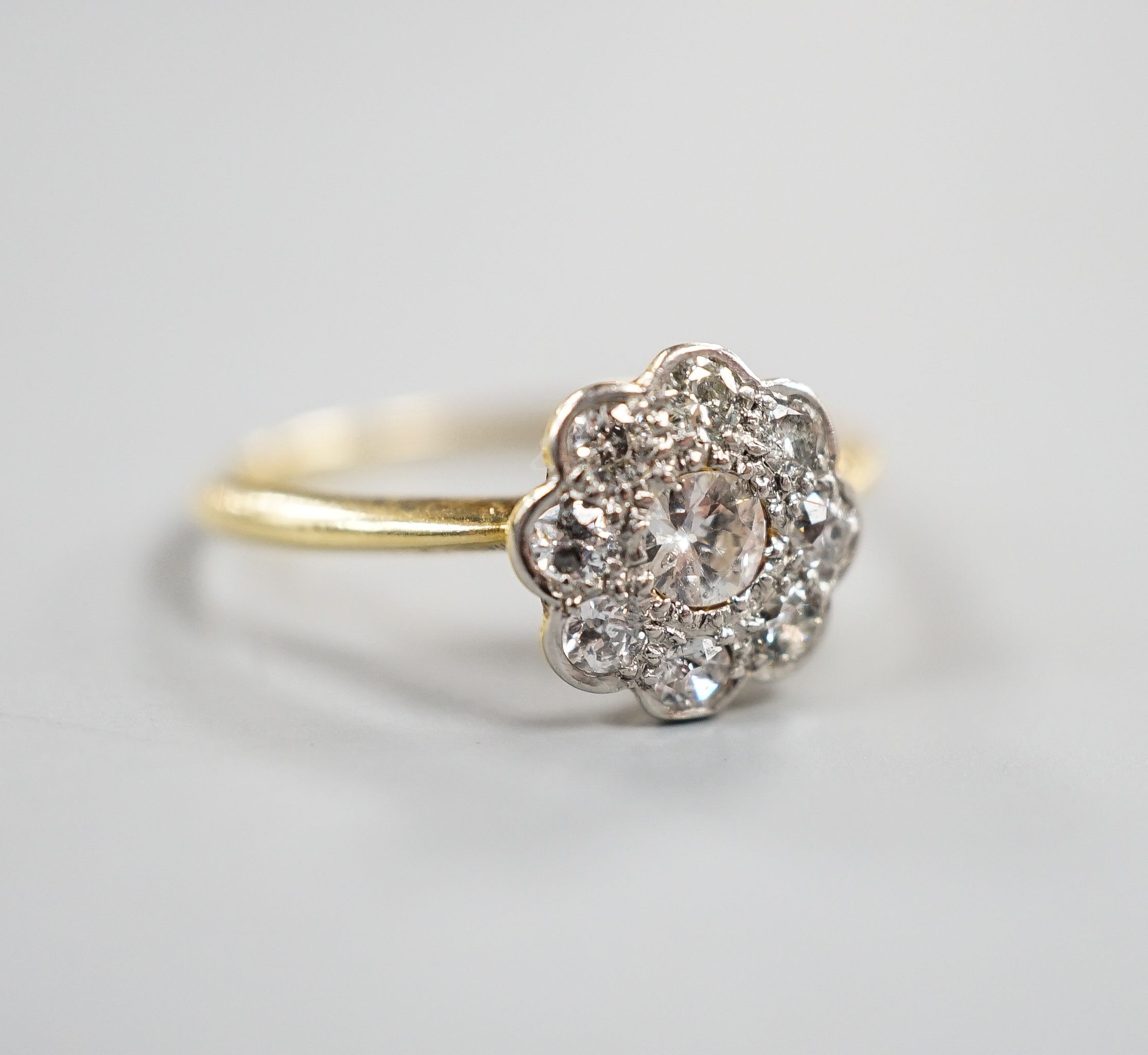 An 18ct, Pt and diamond set flower head cluster ring, size N, gross weight 2.4 grams.